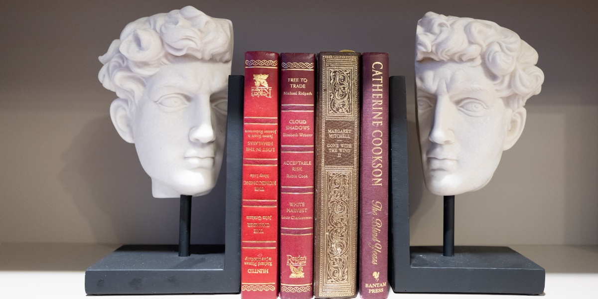Bookends with greek statue heads supporting a selection of books