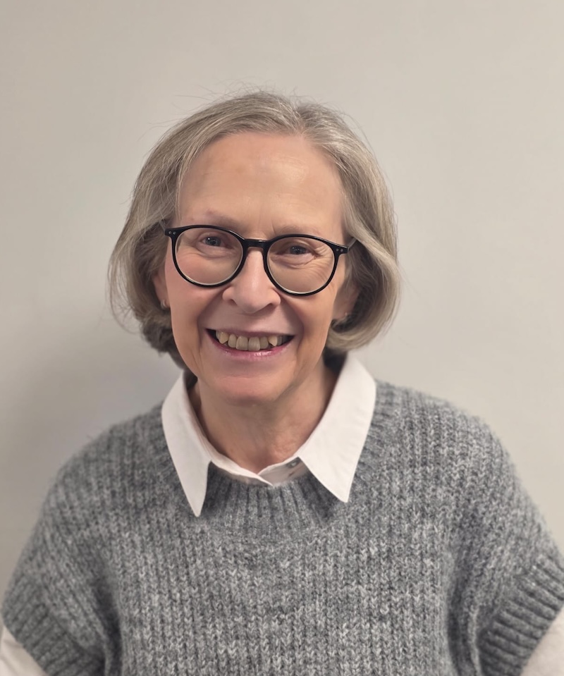 woman with silver hair and a white shirt and grey jumper on smiling having a headshot taken for the Rowan Park team page