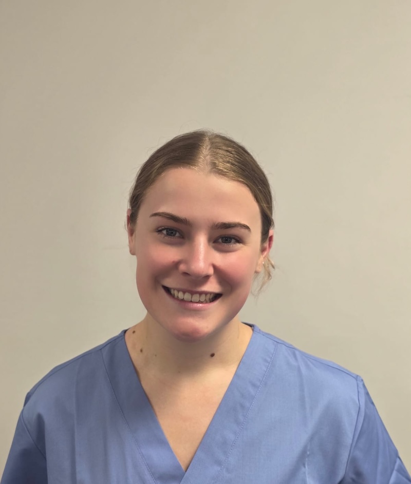 woman with blonde hair tied back in a ponytail smiling with a blue carers uniform on having a headshot taken for the Rowan Park team page