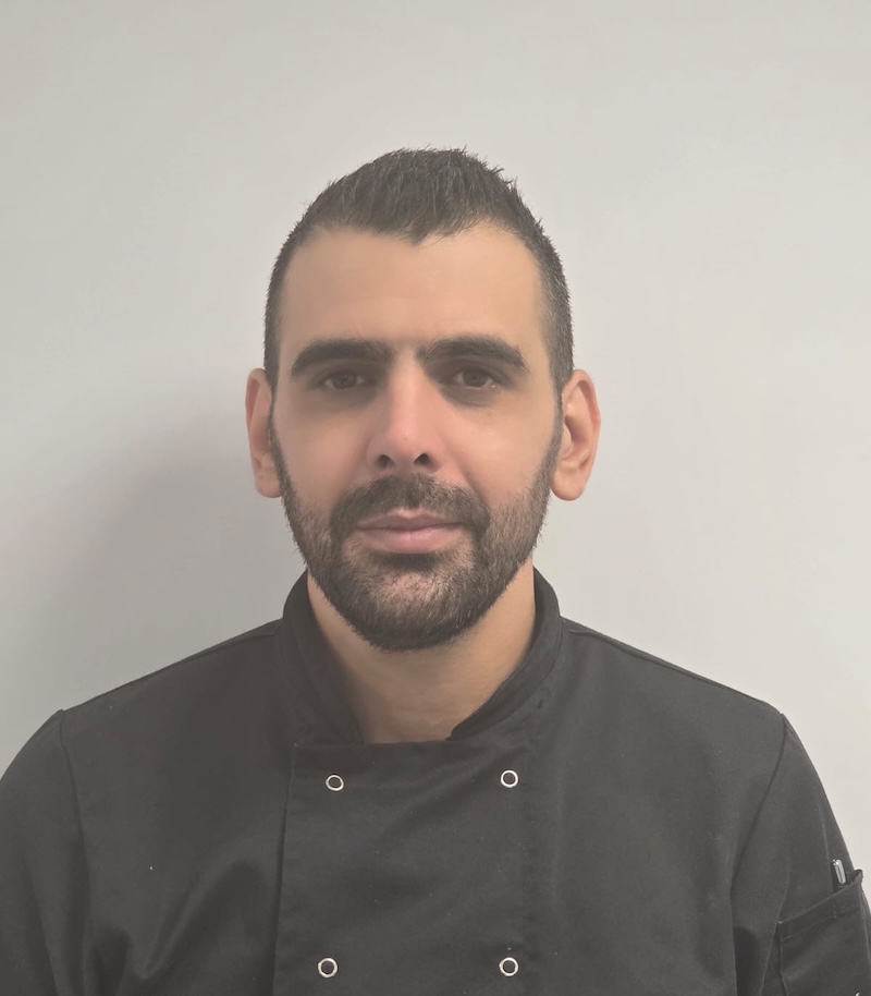 man with short brown hair and black chef uniform on having a headshot taken for the Rowan Park team page