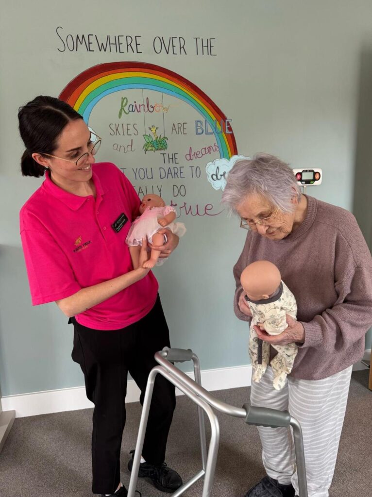 resident doing doll therapy with a carer