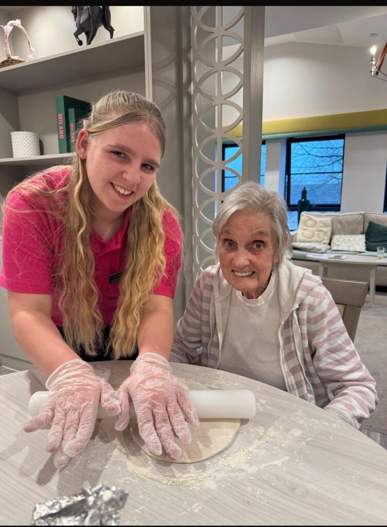 resident baking and rolling out dough with carer