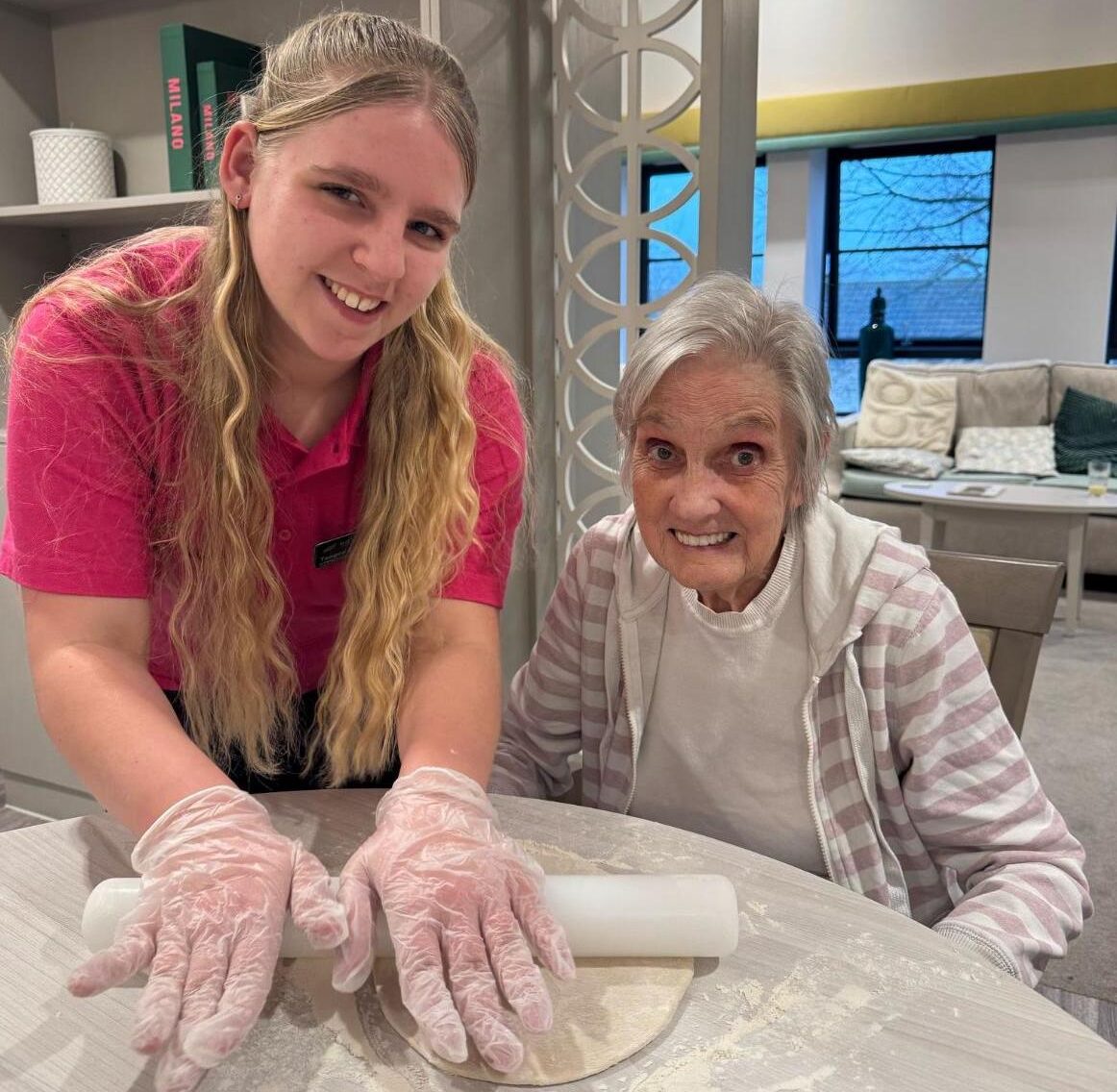 resident baking and rolling out dough with carer