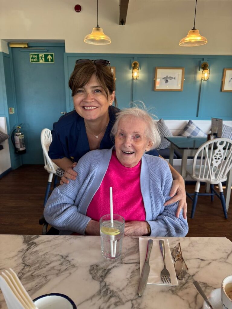 female resident and carer smiling together in a cafe