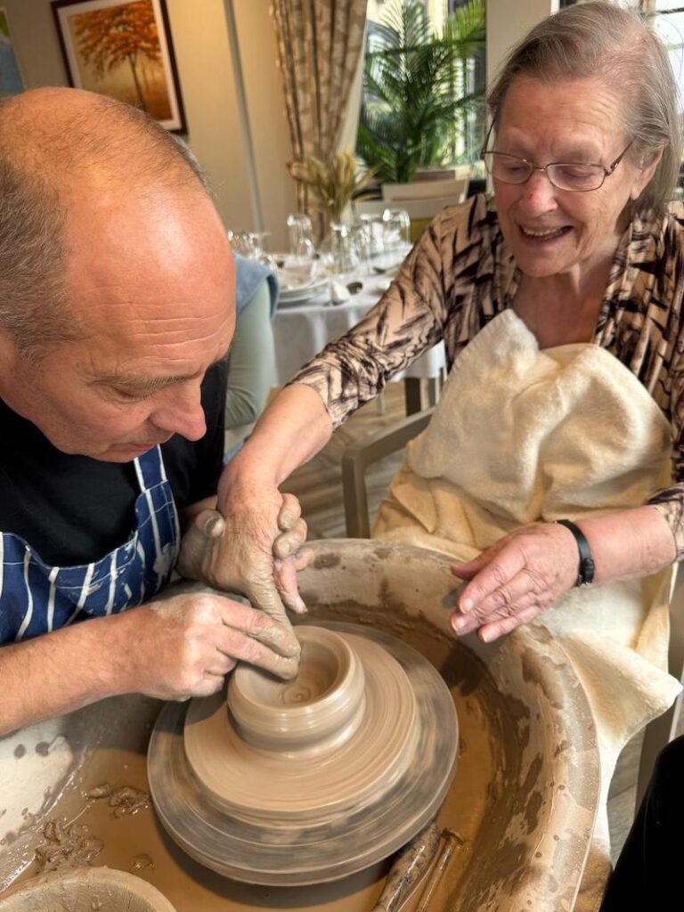 one of our female residents sat next to the pottery man helping to shape clay