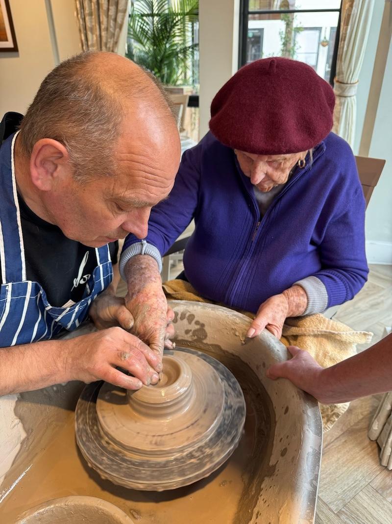 one of our female residents sat next to the pottery man helping to shape clay
