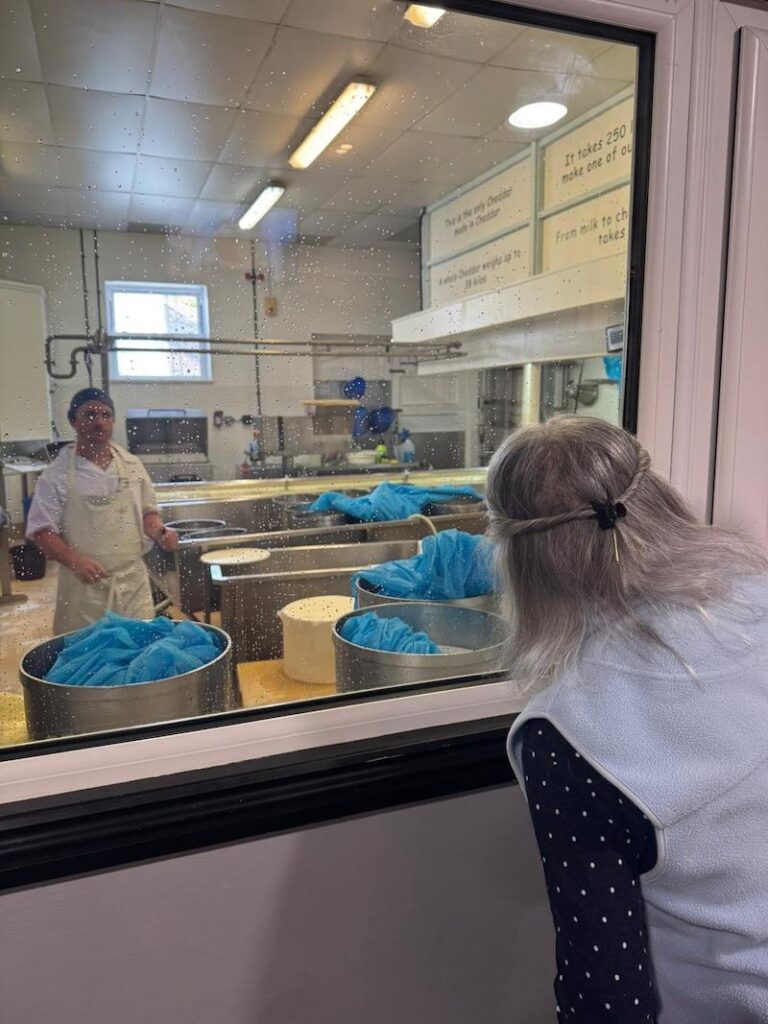 resident looking through the window at cheese being made