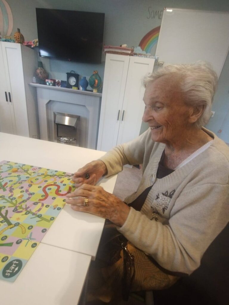female resident smiling playing snakes and ladders