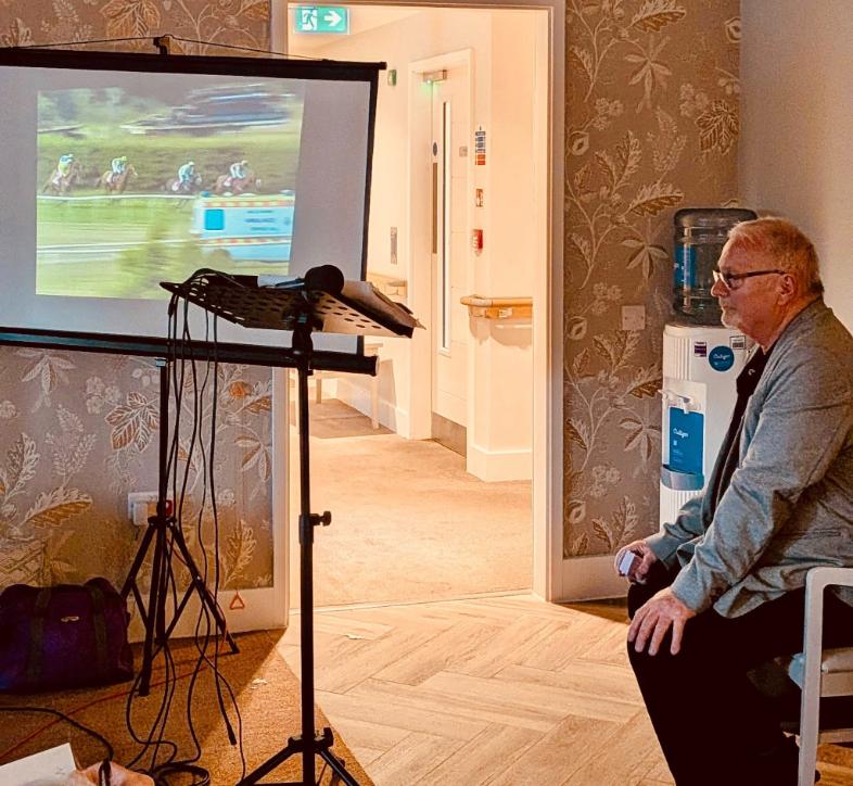 older man sitting down watching horse racing
