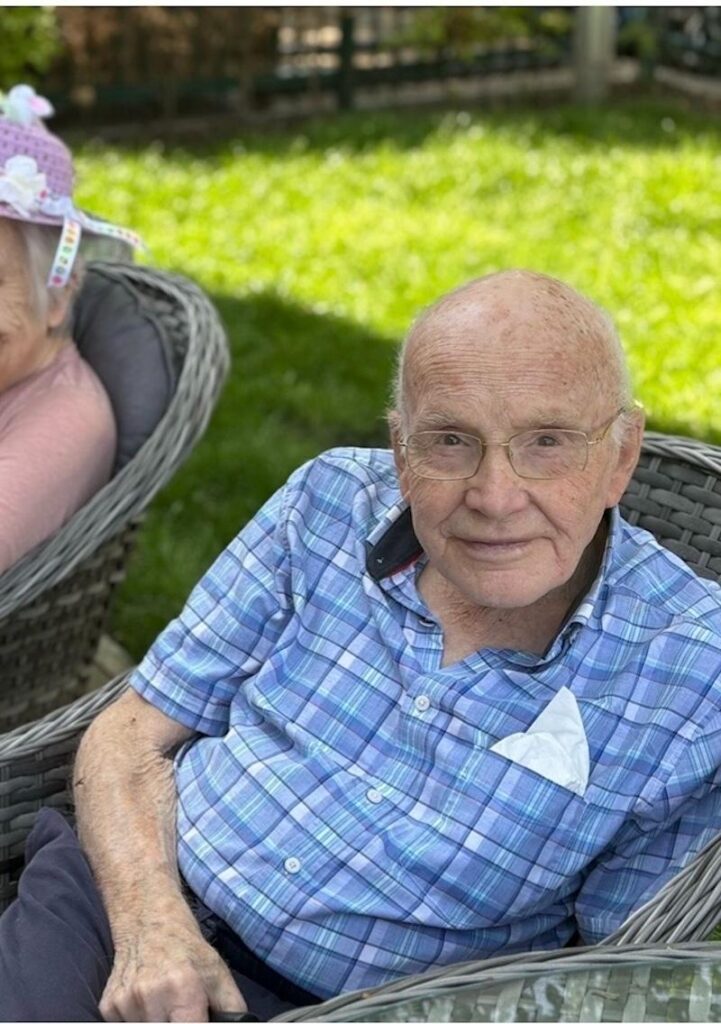 male resident wearing a blue shirt sat outside smiling