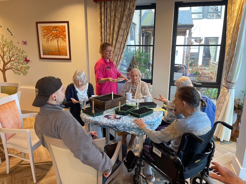 a group of residents sat around a table together doing indoor gardening