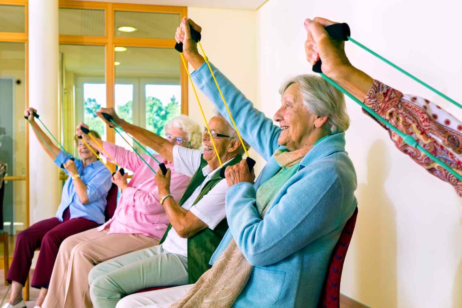 a group of residents doing seated arm exercises with resistance bands