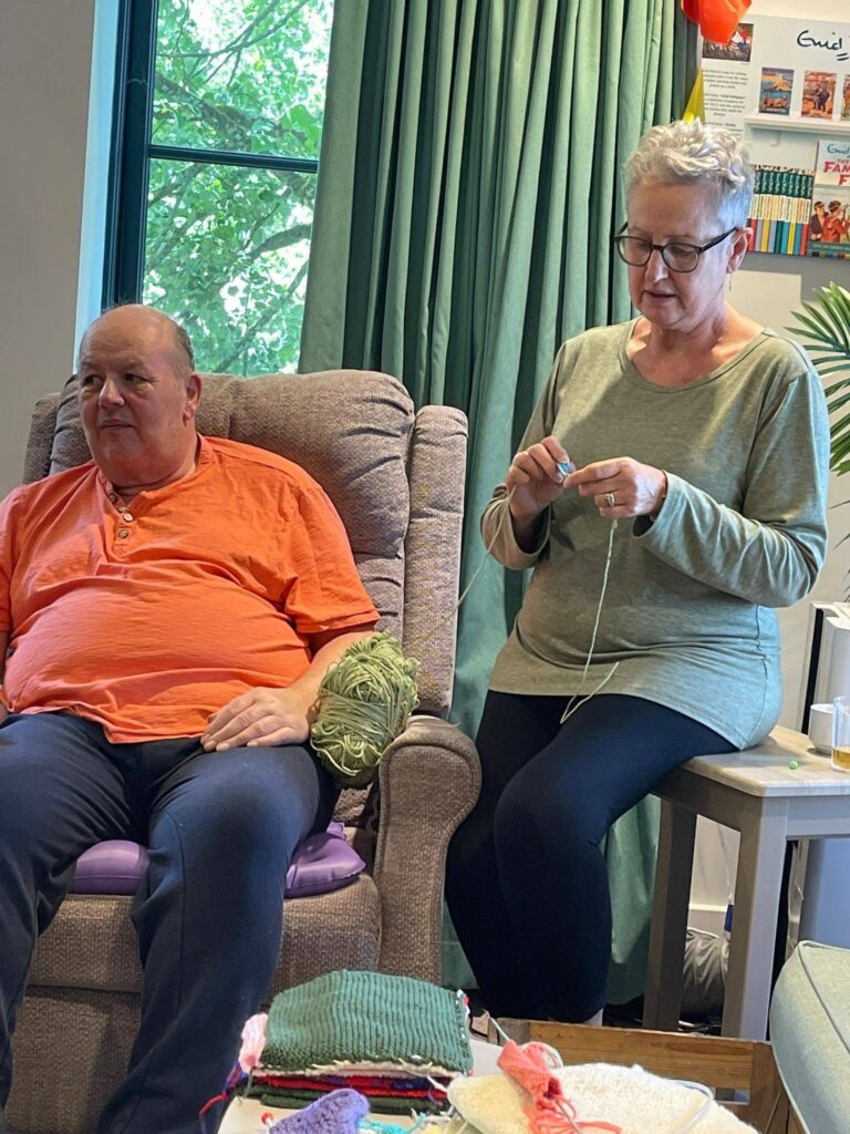 an older lady knitting sat next to a man
